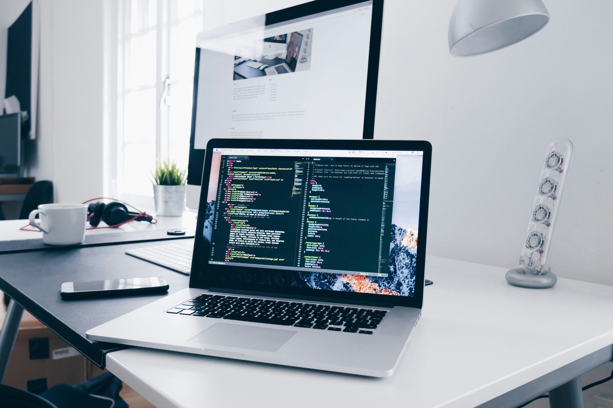 Photo of a macbook on a desk, with code on the screen